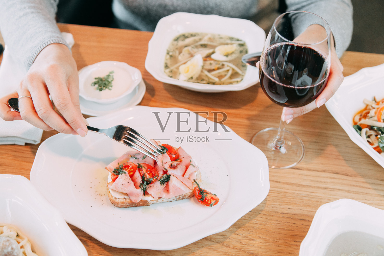 这个女孩正在吃烤面包加培根和番茄。菜单上餐馆的菜和酒。照片摄影图片