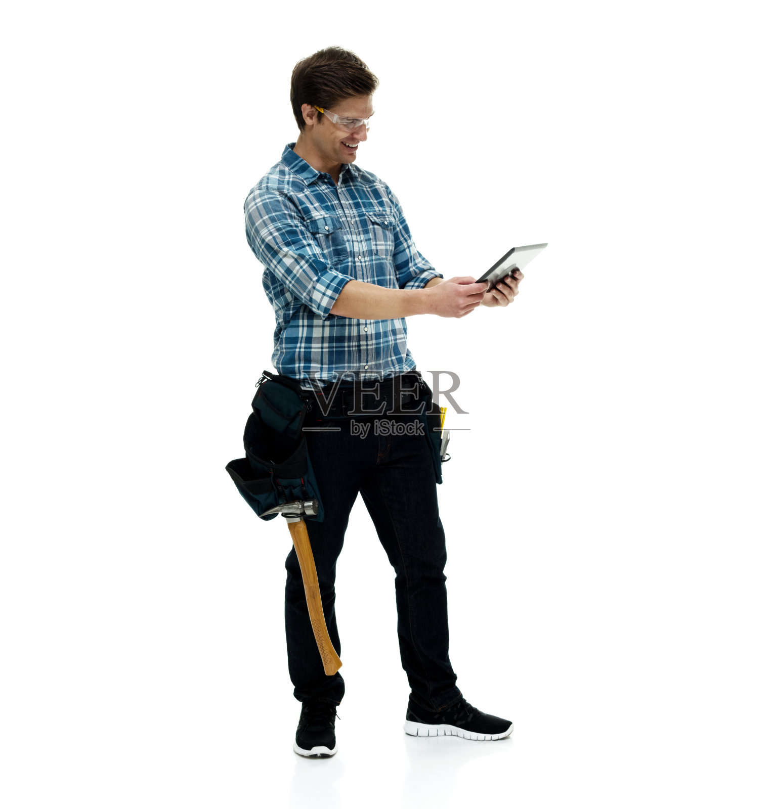 白人年轻男性建筑工人站在白色背景下，穿着格子衬衫，使用数码平板电脑照片摄影图片