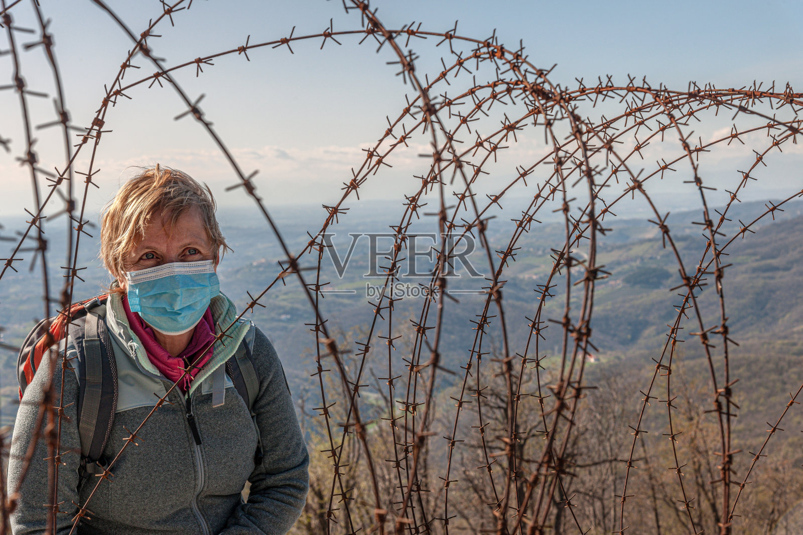 欧洲斯洛文尼亚的带刺铁丝网年长妇女- Covid-19造成的检疫概念照片摄影图片