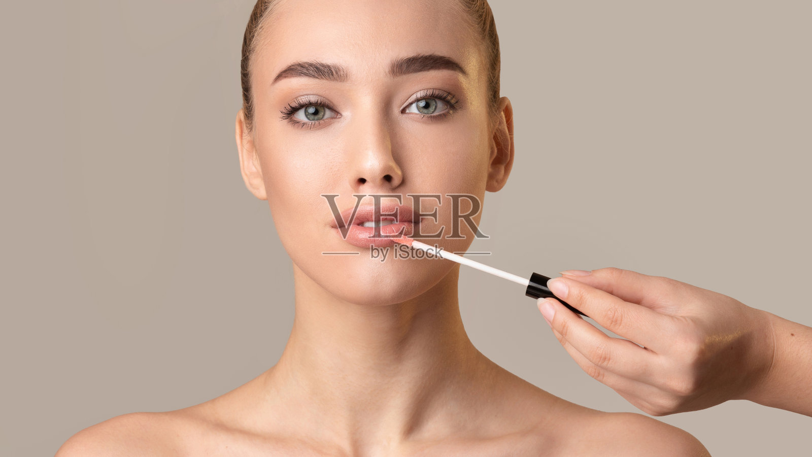 模特女孩在米色背景上用口红看着相机照片摄影图片