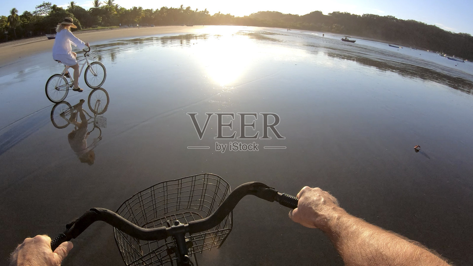 日出时分，一对成熟的夫妇在海滩上骑自行车照片摄影图片