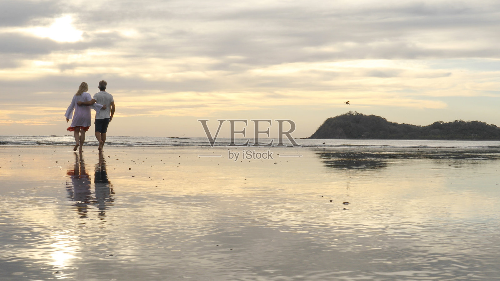 一对夫妇在日出时沿着海滩散步照片摄影图片