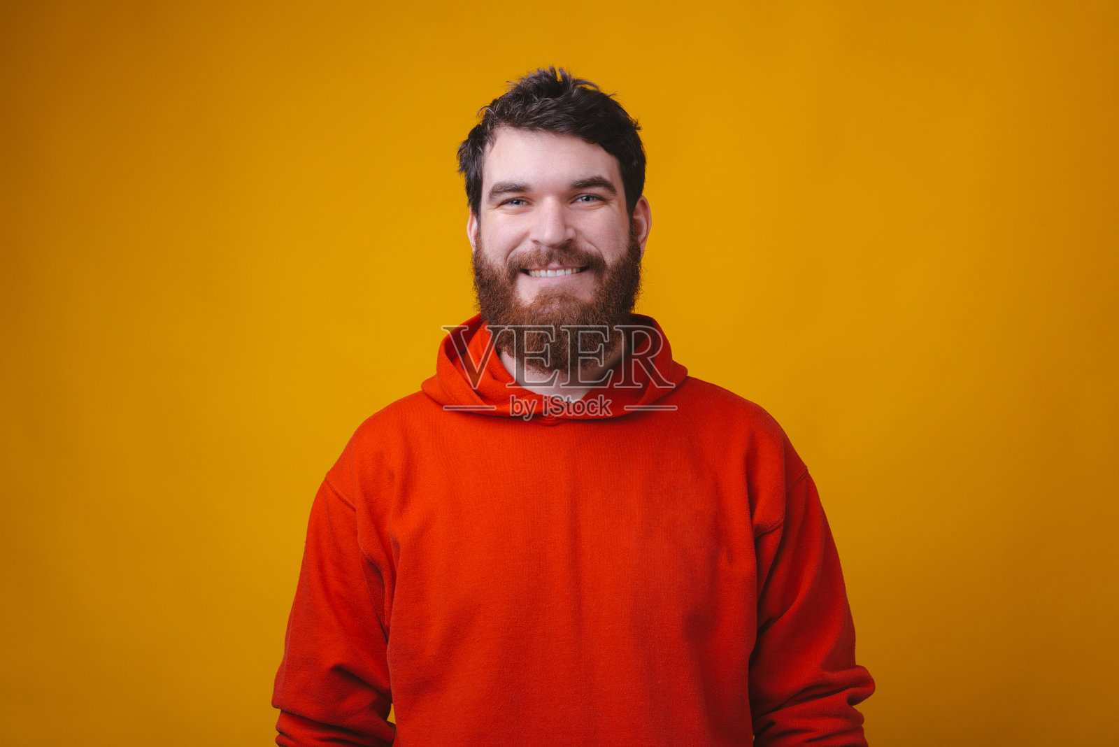 一幅穿着红色衬衫、满脸胡须、面带微笑的嬉皮士男子看着镜头的肖像照片摄影图片