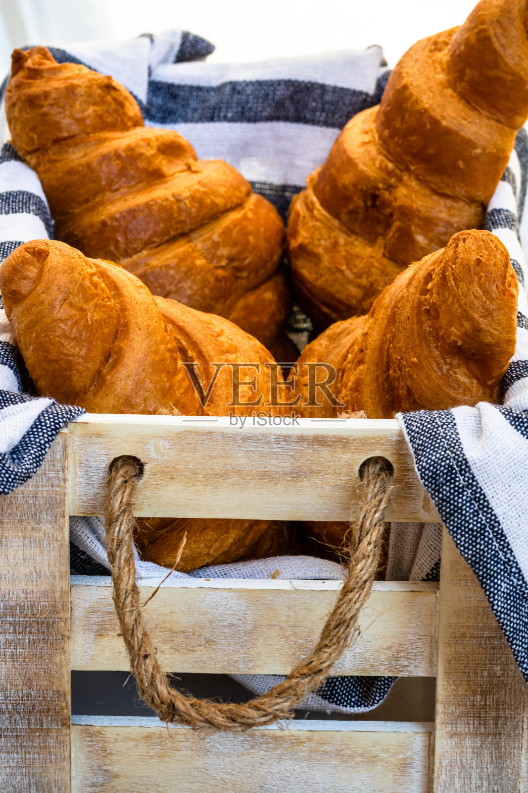 新鲜牛角面包，酥皮和黄油法式牛角面包装在木箱里。食物和早餐的概念。甜点和新鲜糕点的细节照片摄影图片