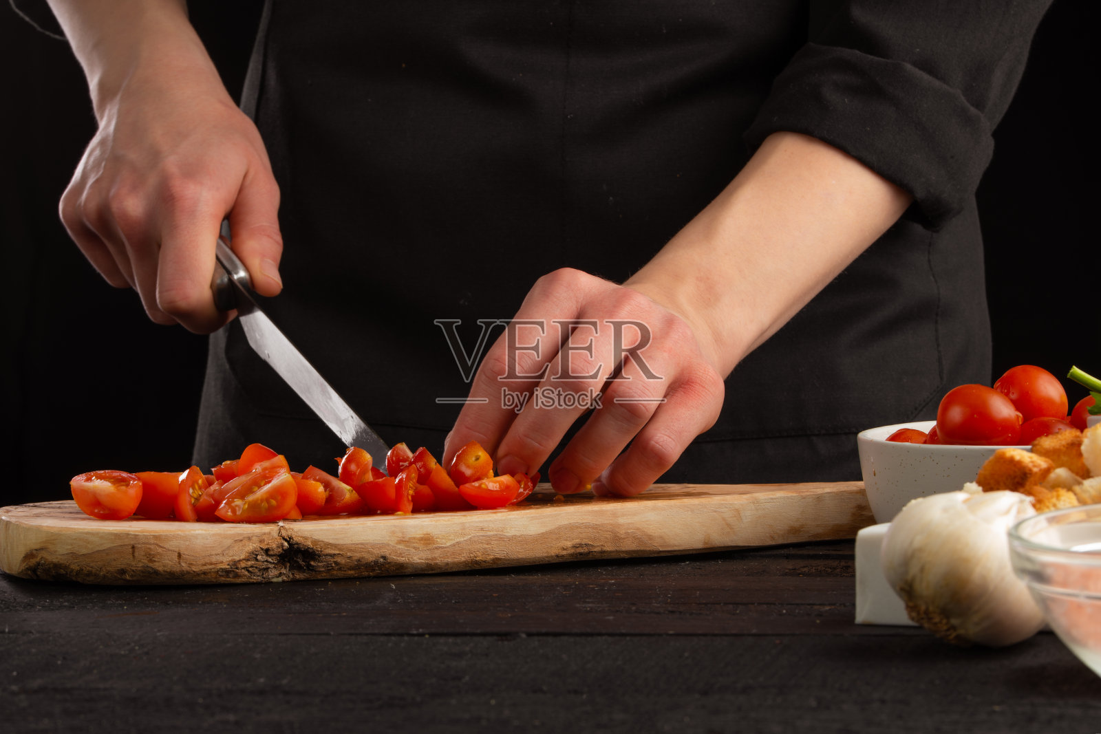 厨师将樱桃番茄切成小片做调味汁。海鲜和东方食谱。照片摄影图片