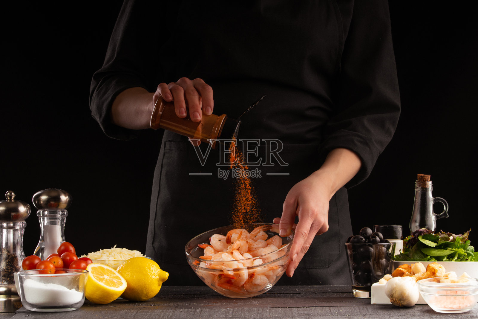 厨师为沙拉烹制虾。海鲜和烹饪。辣椒，动态冷冻。美味和健康的食物在黑色的背景。照片摄影图片