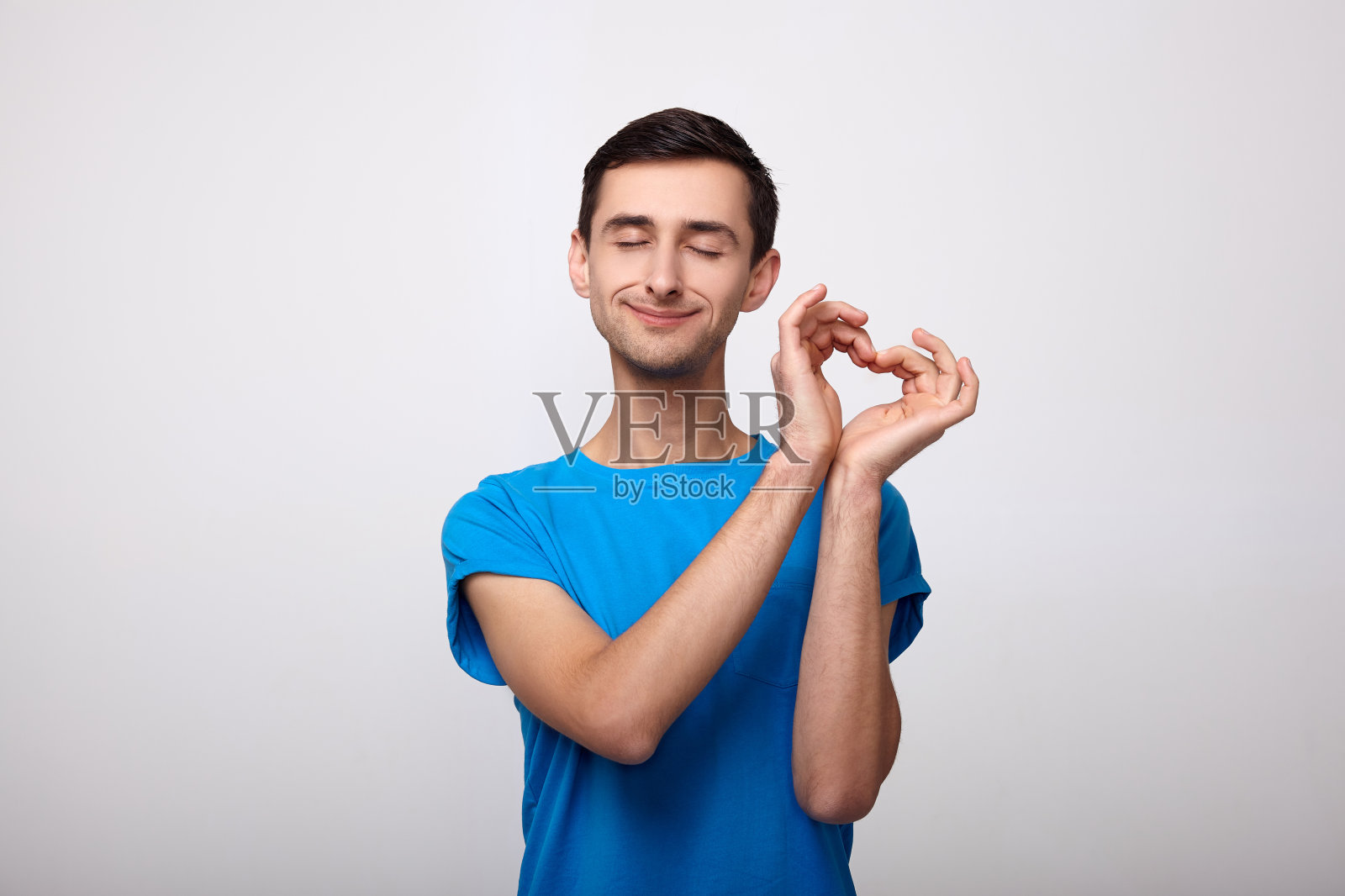 肉欲的年轻人闭上眼睛，用手表示他的心。照片摄影图片