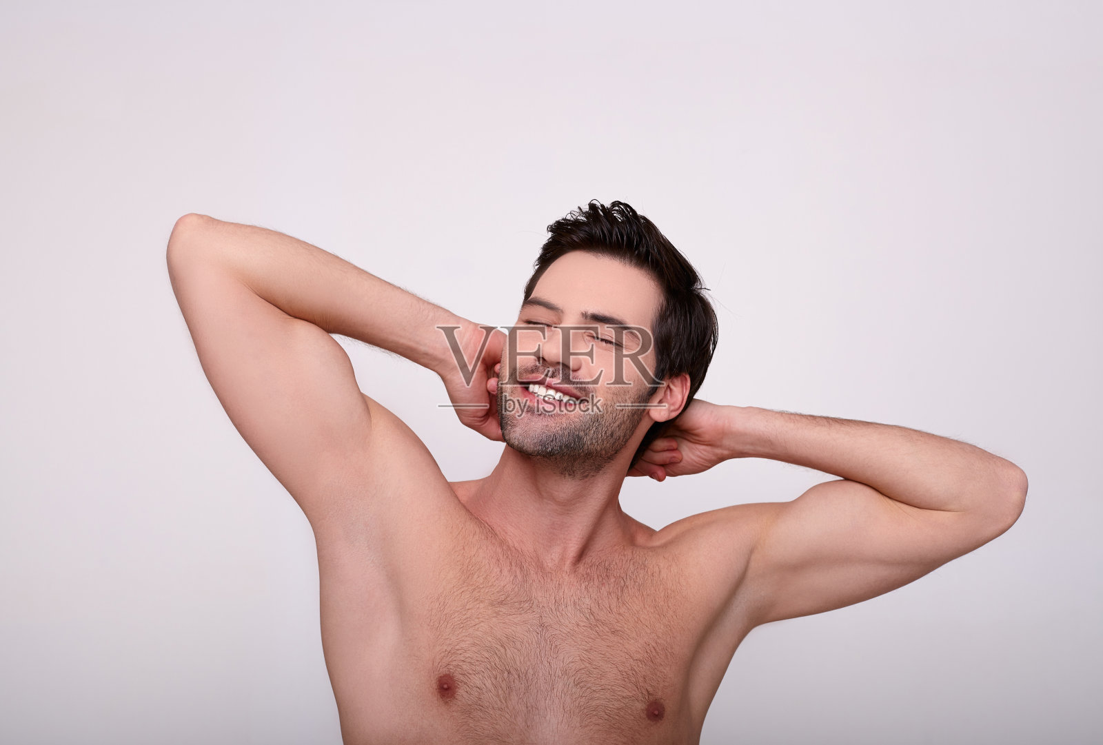 男子在浅色背景下展示光滑的腋窝照片摄影图片