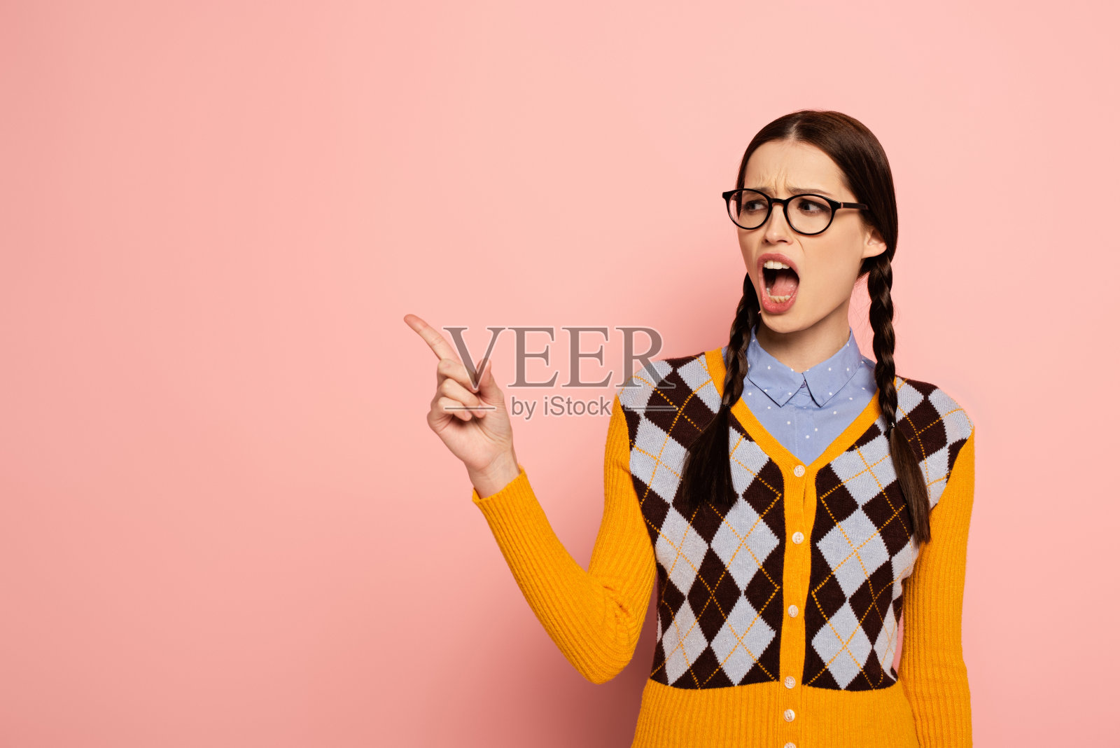 一名戴眼镜的女书呆子用手指着粉红色照片摄影图片