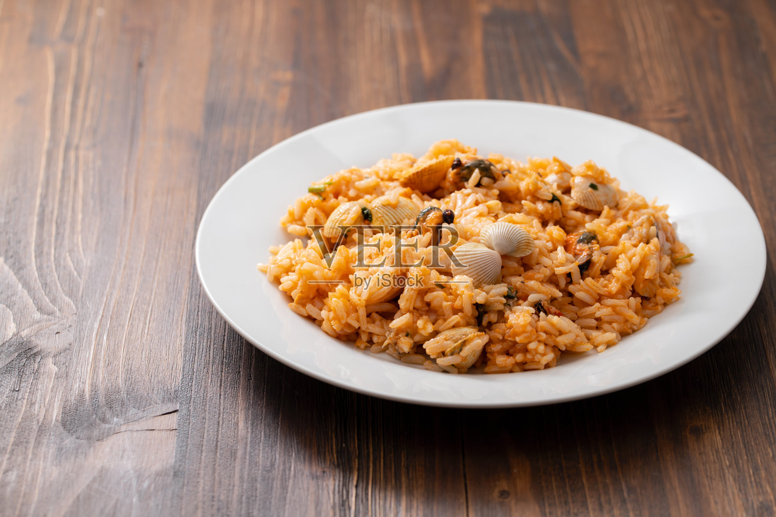 米饭配海鲜，白色的盘子，棕色的木背景照片摄影图片