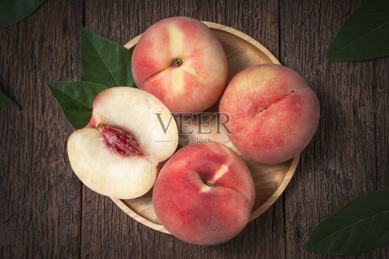 旧木桌上放着带叶子的桃子。新鲜的白色桃子在木制的背景照片摄影图片