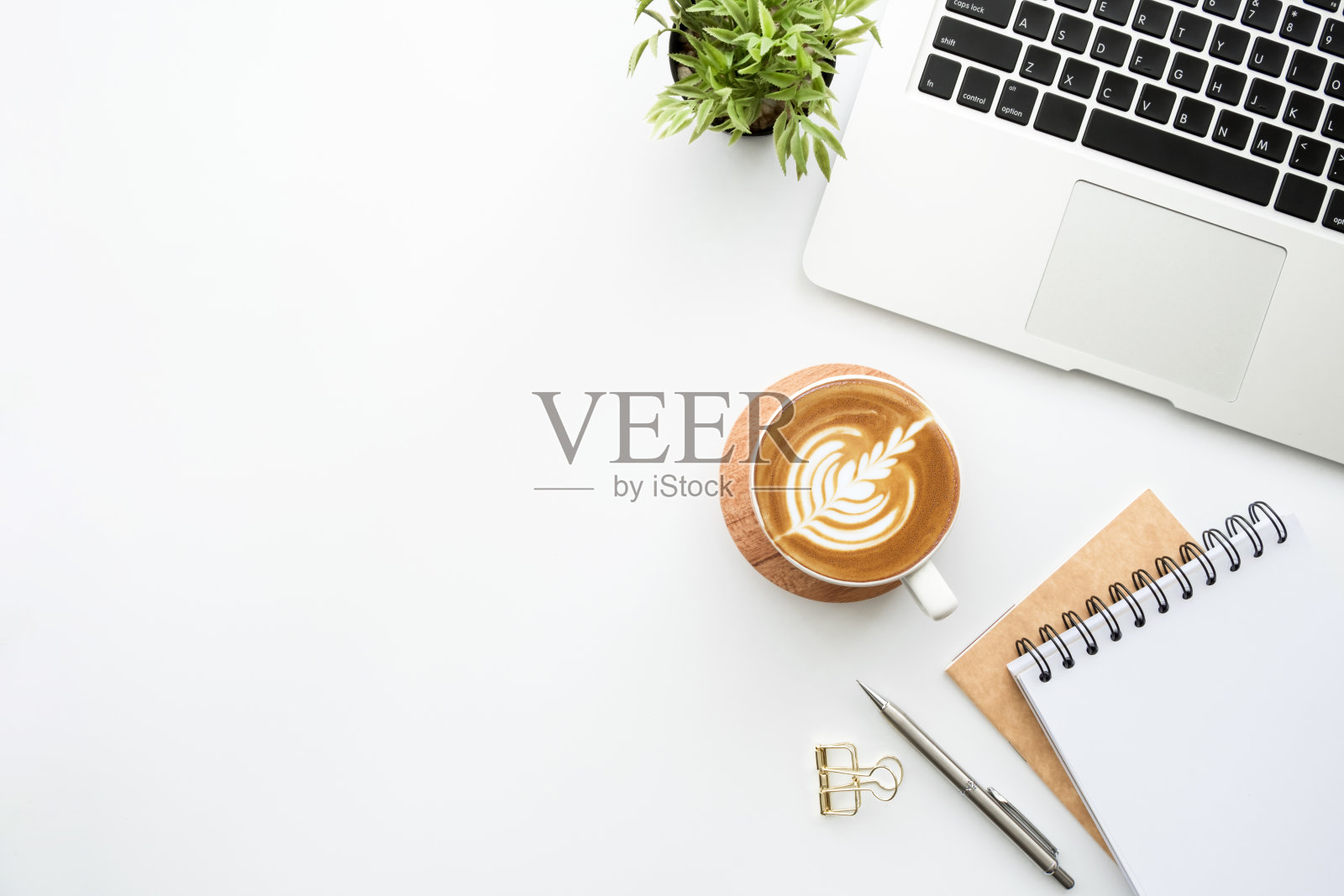 白色的极简主义办公桌上有笔记本电脑，带笔的笔记本，一杯拿铁咖啡和其他用品。顶视图与复制空间，平放。照片摄影图片