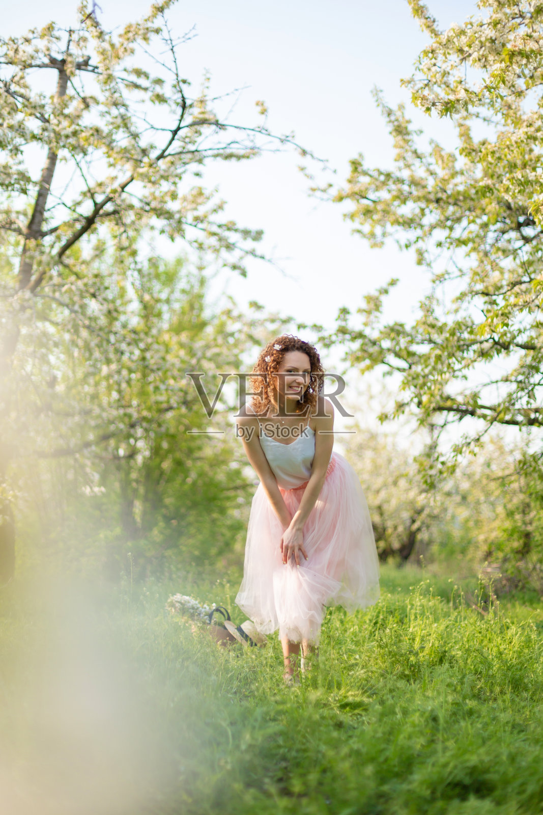 年轻有魅力的女孩在春天绿色的公园里享受着鲜花盛开的景色照片摄影图片