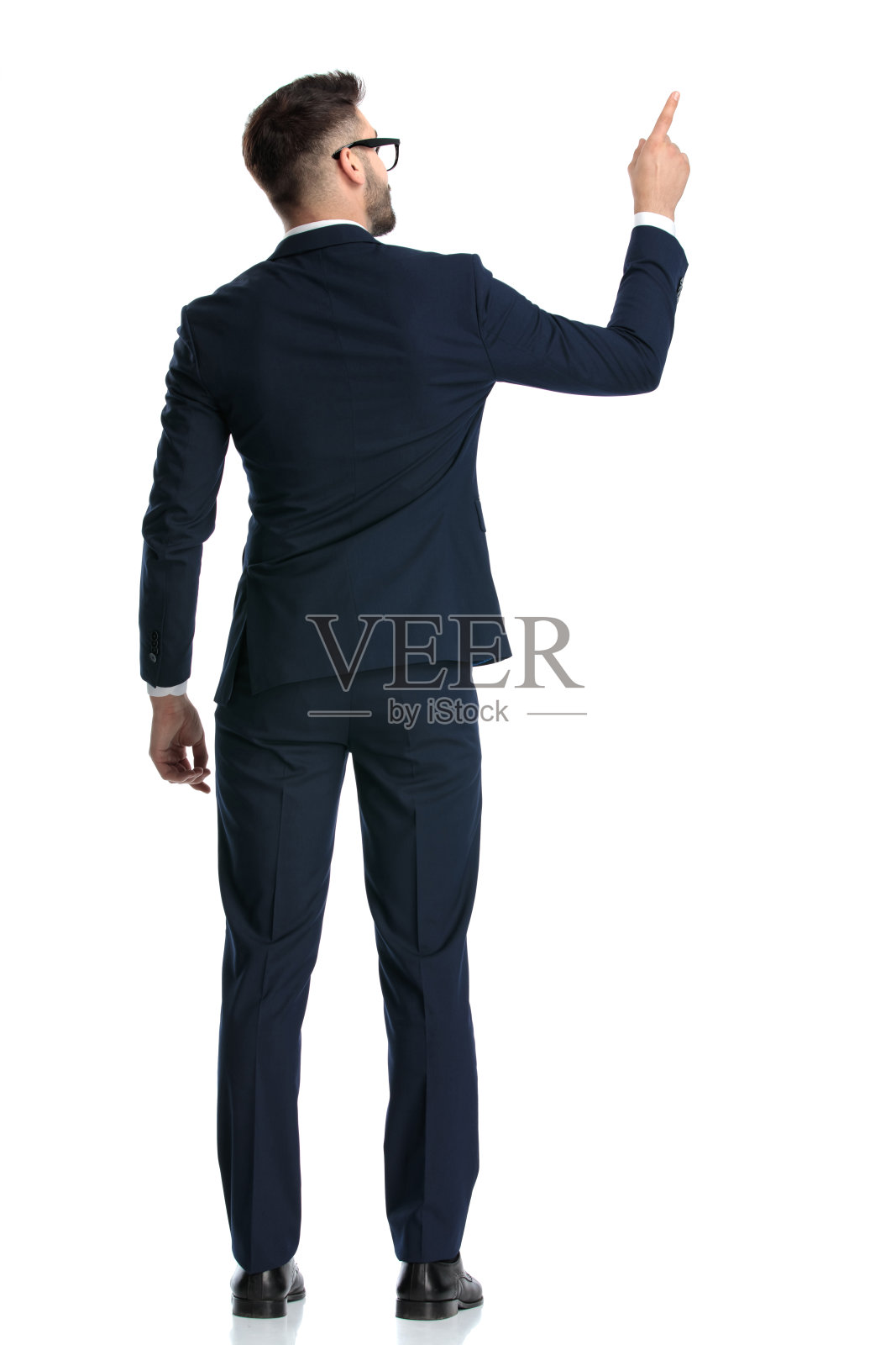 年轻的商人戴着眼镜站着，指着上面照片摄影图片