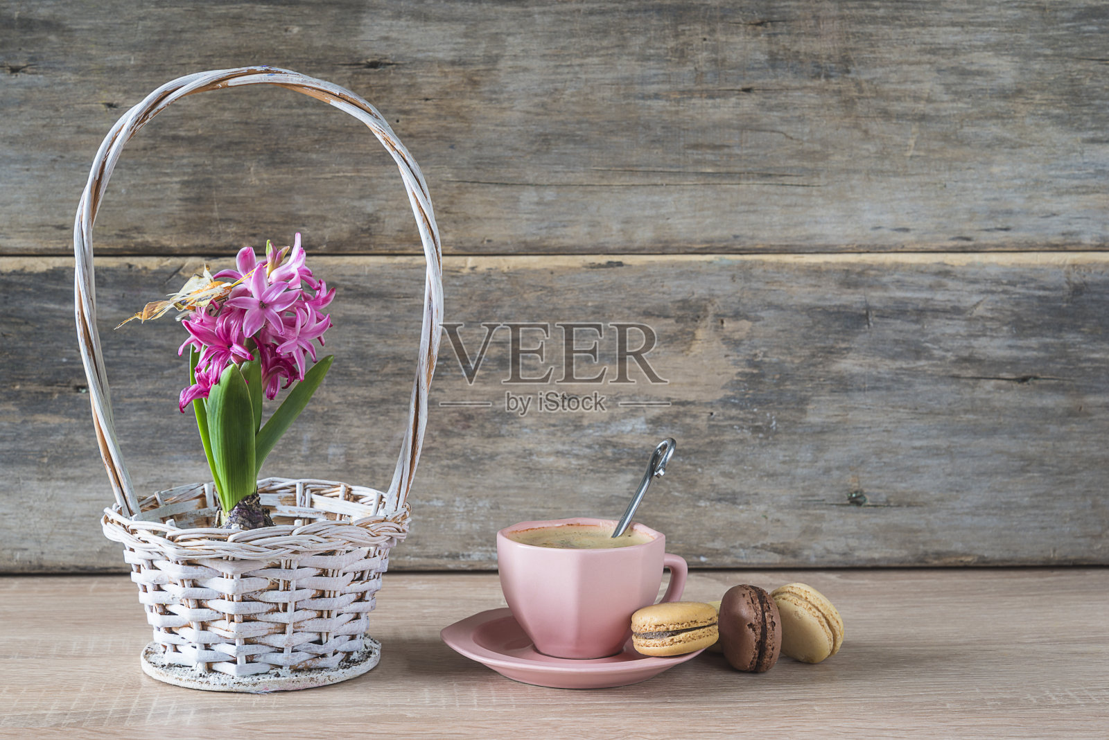 一杯咖啡，法国杏仁饼干和紫色的风信子花在柳条篮子的木制背景。空间的文本照片摄影图片