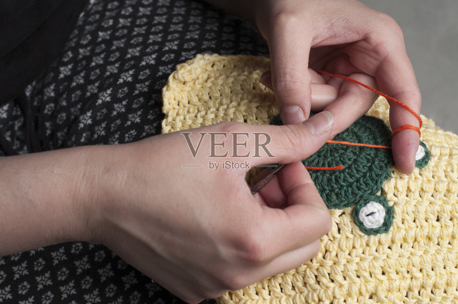 女人编织钩针。这个女孩坐在沙发上编织毛线。照片摄影图片