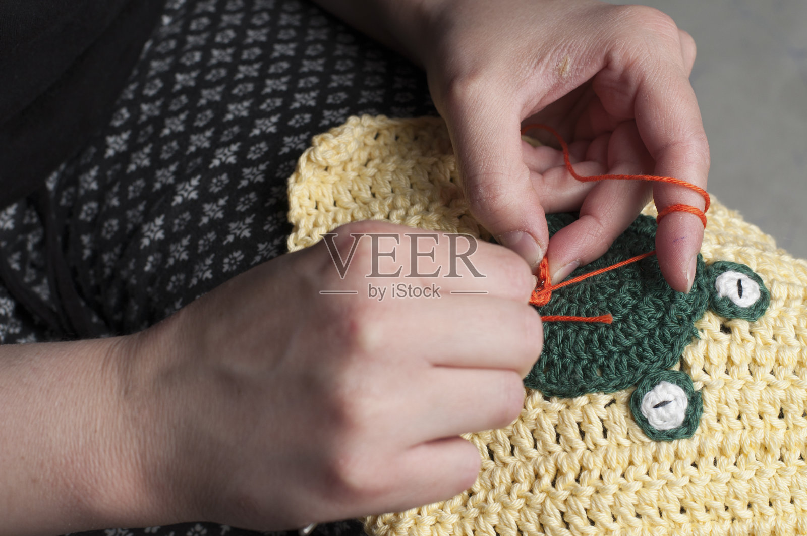 女人编织钩针。这个女孩坐在沙发上编织毛线。照片摄影图片