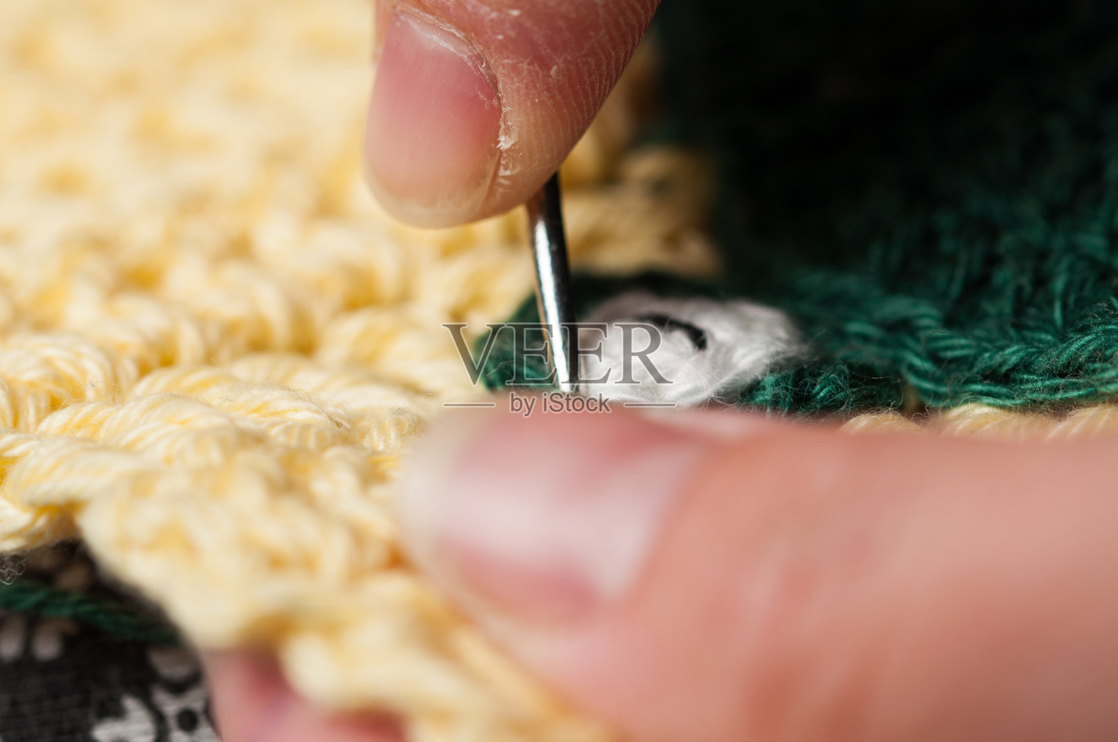 女人编织钩针。这个女孩坐在沙发上编织毛线。照片摄影图片