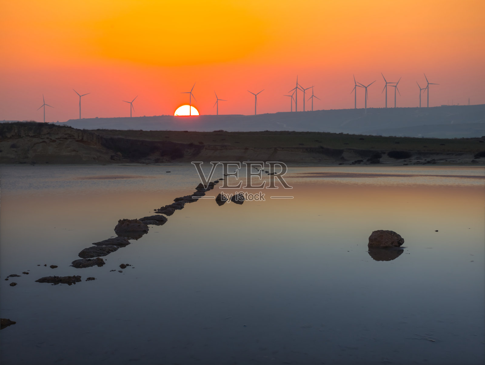 桂特湖在夕阳下，风力发电站的剪影在夕阳下，绿色能源的背景照片摄影图片