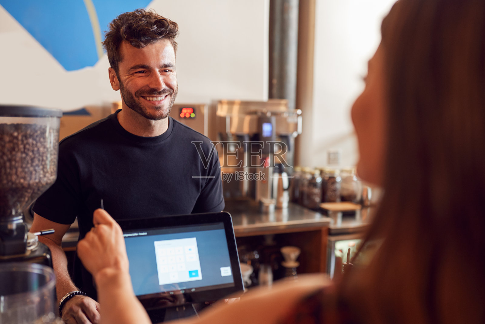 女顾客在咖啡店销售柜台为咖啡师付款照片摄影图片