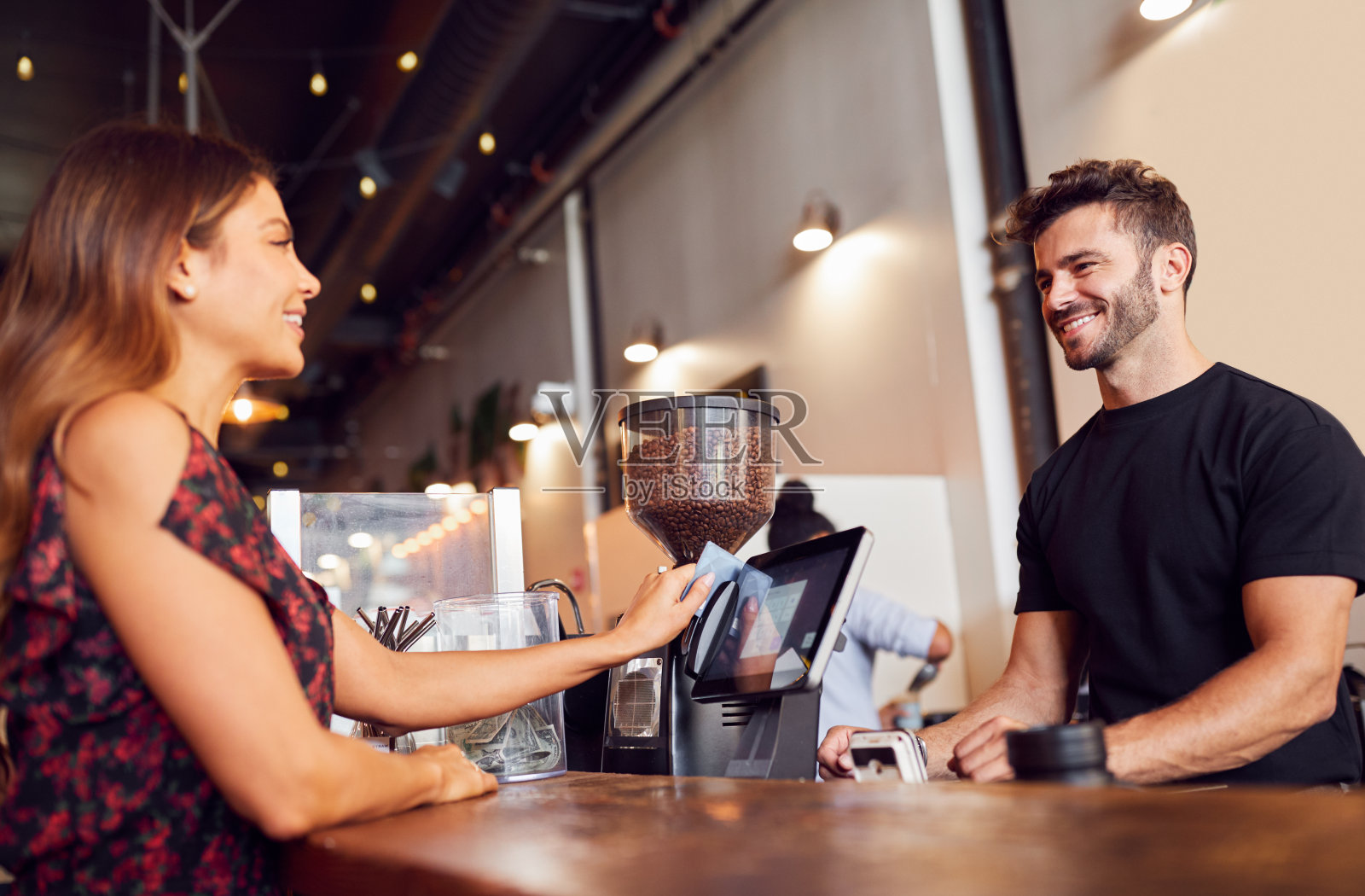 女顾客在咖啡店销售柜台为咖啡师付款照片摄影图片