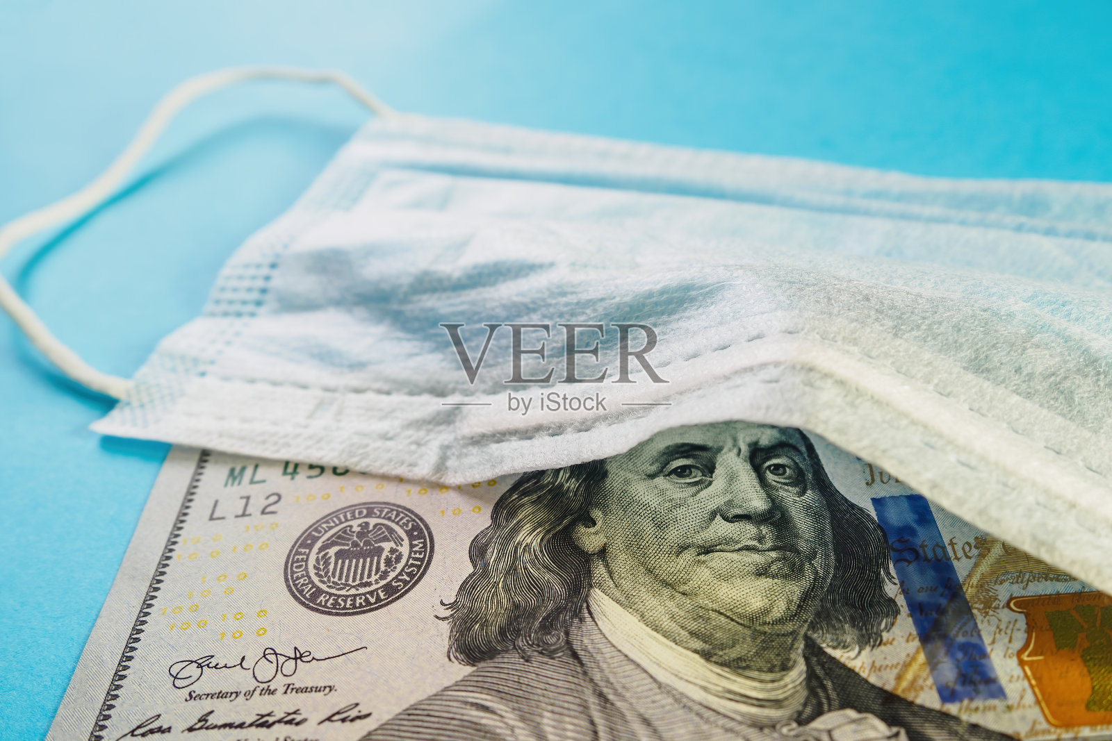 医用口罩和蓝色背景的100美元钞票。概念亏空，炒作口罩售罄照片摄影图片