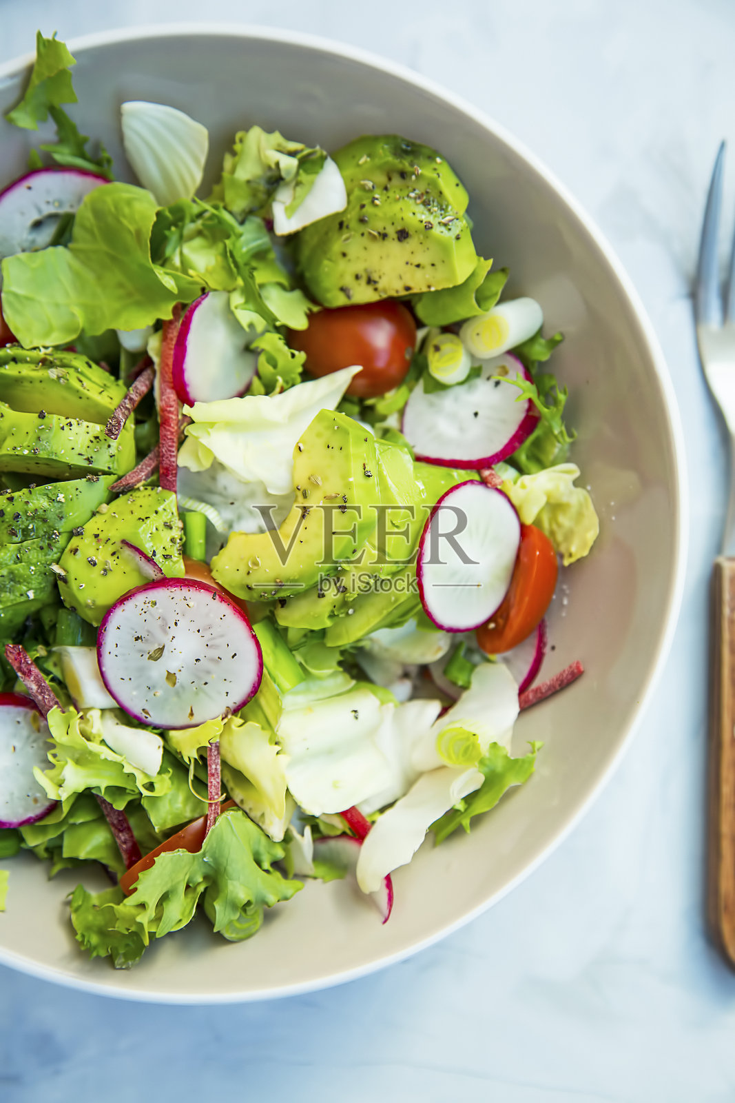 新鲜蔬菜沙拉碗特写，健康的有机蔬菜沙拉与萝卜，菠菜，西红柿，洋葱，鳄梨照片摄影图片