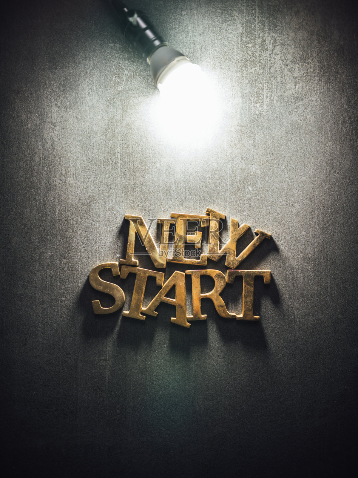 开始文本金色和发光灯泡在灰色的桌子背景照片摄影图片