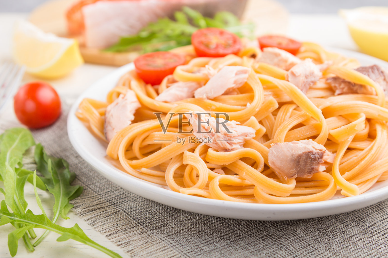 粗面粉意面，鲑鱼和鲑鱼排在白色的木质背景和亚麻纺织品。侧视图，特写，选择性聚焦。照片摄影图片