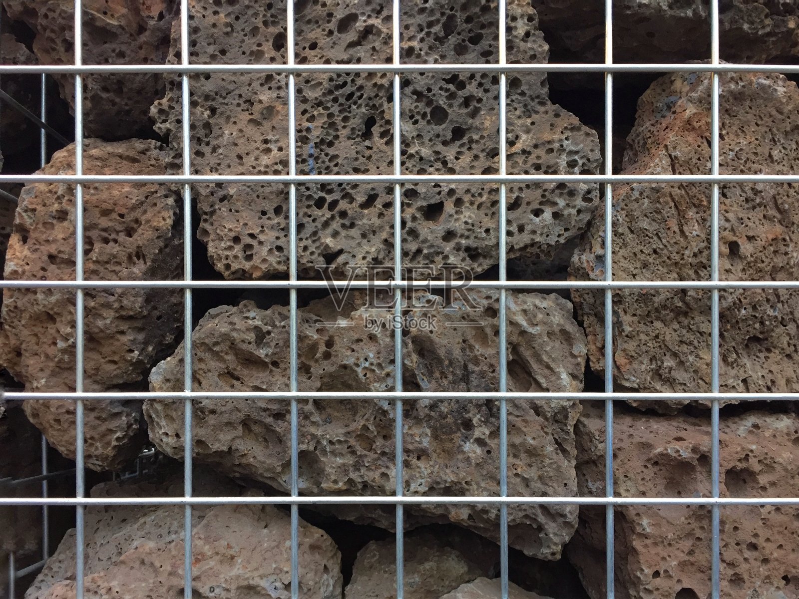 石头紧紧地堆放在铁丝网里照片摄影图片