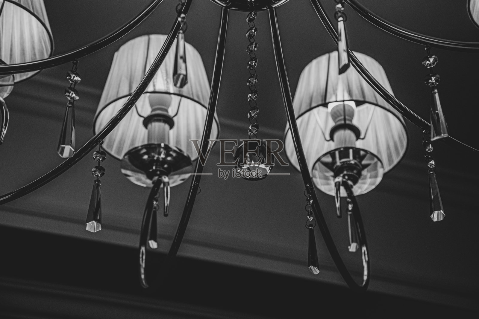 柔和的焦点维多利亚风格的灯的细节。复古吊灯的特写与白色灯罩和闪亮的透明水晶悬挂和珠宝形状的玻璃吊坠。黑白照片。照片摄影图片
