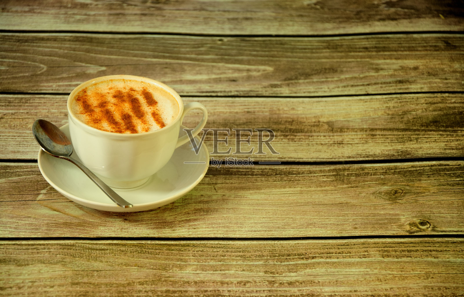 木桌上放着一只瓷杯，上面放着新鲜的卡布奇诺，上面装饰着肉桂和茴芹。照片摄影图片