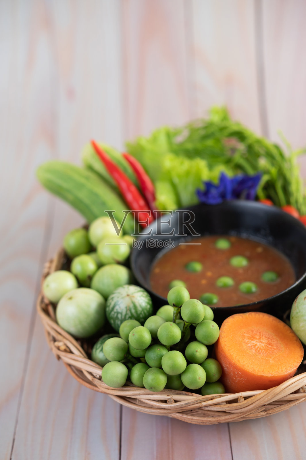 辣椒酱装在碗里，用茄子、胡萝卜、辣椒、黄瓜装在木桌上的篮子里照片摄影图片