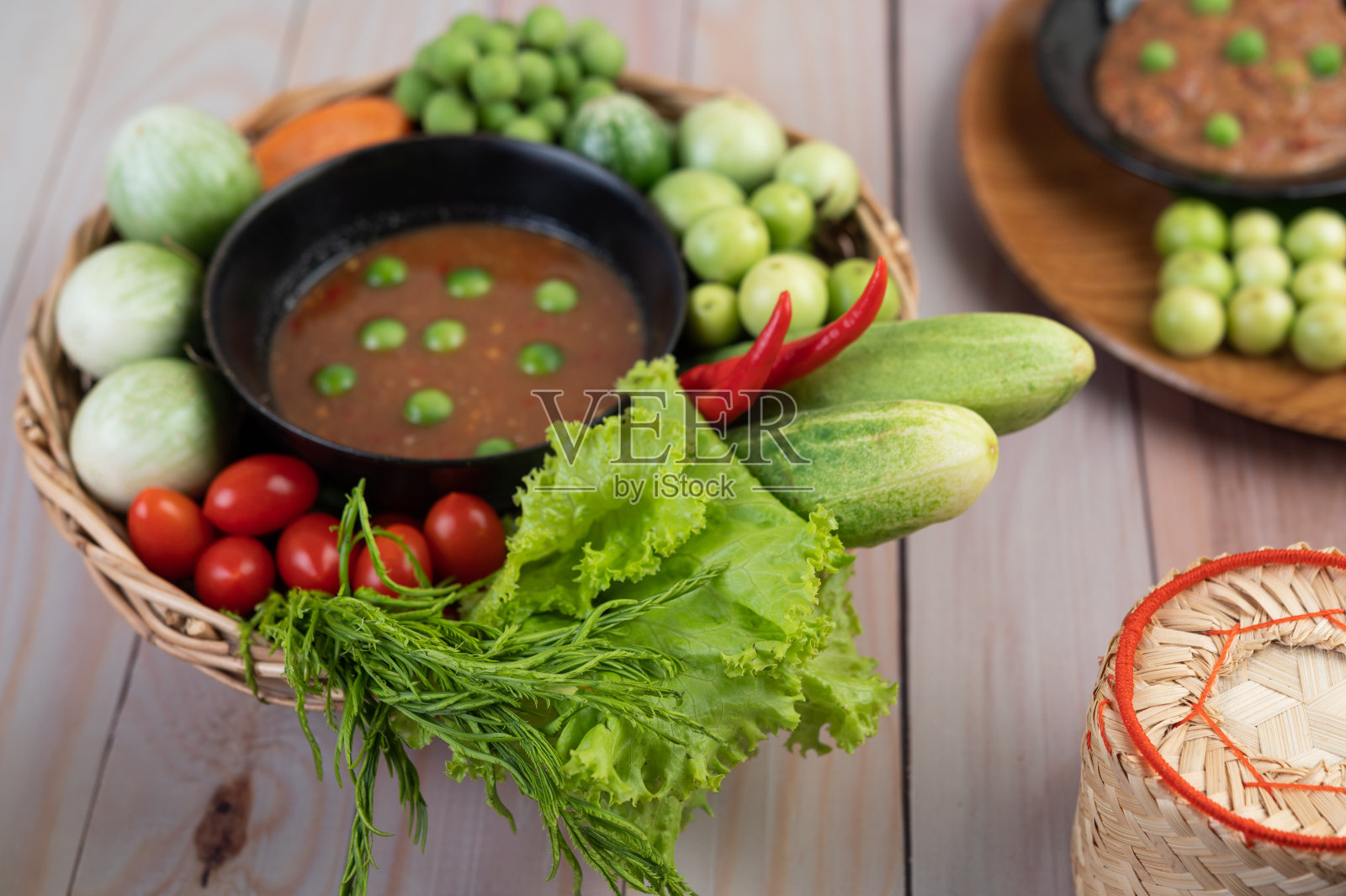 辣椒酱装在碗里，用茄子、胡萝卜、辣椒、黄瓜装在木桌上的篮子里照片摄影图片