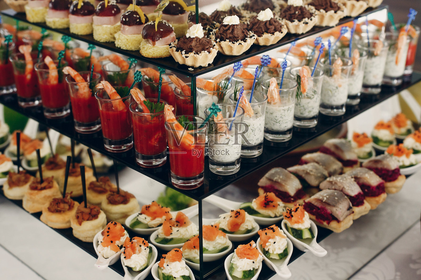 在豪华餐厅婚宴餐桌上的美味小吃，虾，海鲜，橄榄和纸杯蛋糕的特写，餐饮理念照片摄影图片