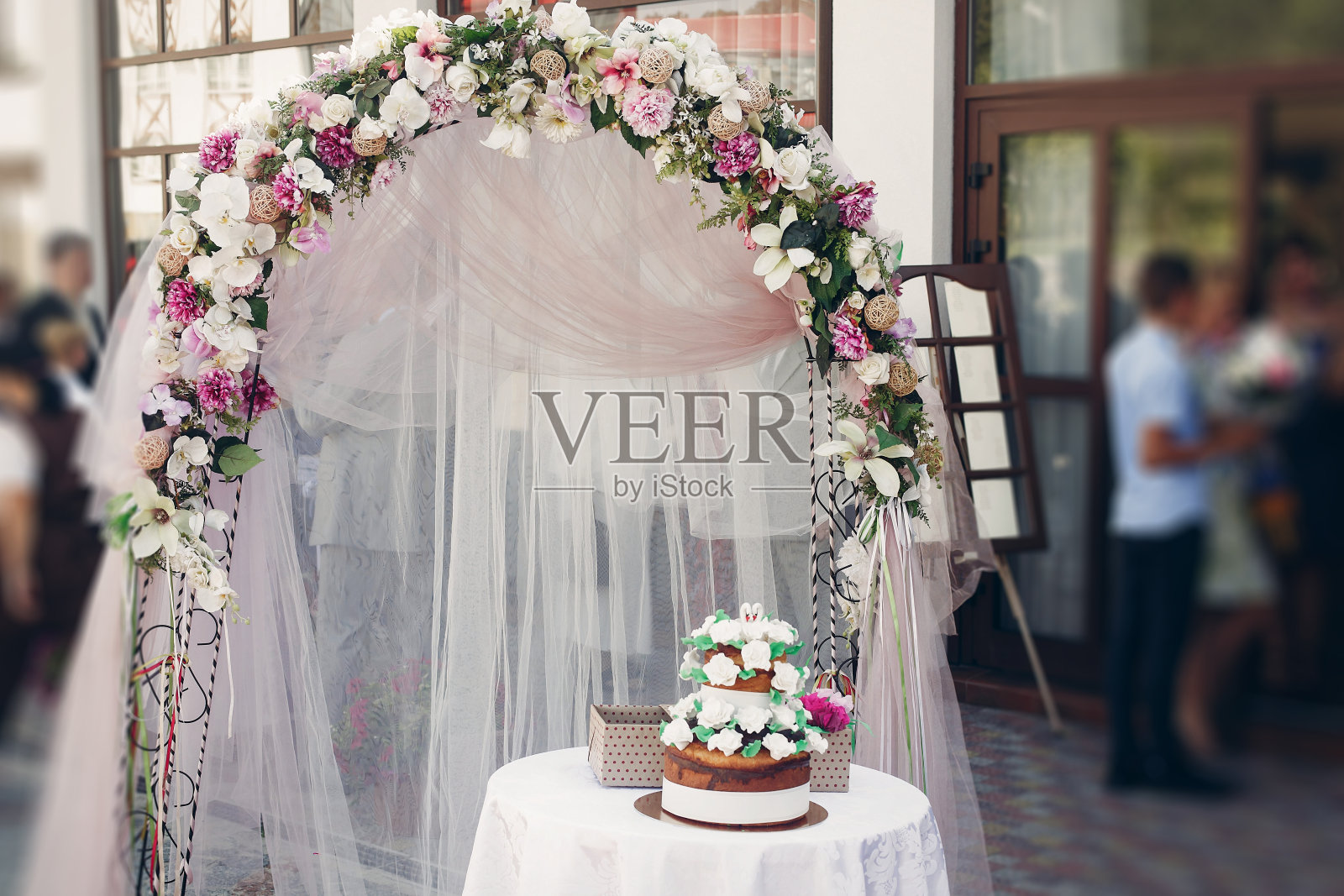 美味装饰巧克力婚礼蛋糕附近的鲜花花环婚礼走廊户外，仪式装饰概念照片摄影图片