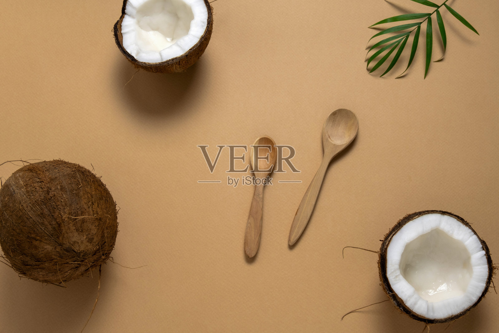 木制的勺子，椰子和绿色的热带树叶在米色的背景照片摄影图片
