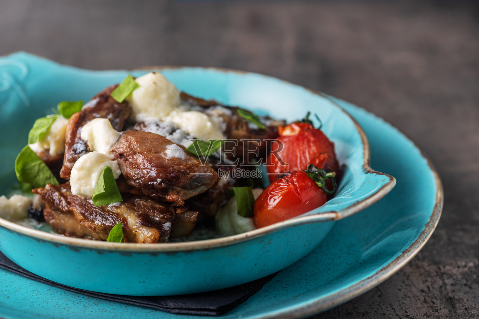 在质朴的厨房桌上放着西红柿和融化的奶酪牛肉。照片摄影图片