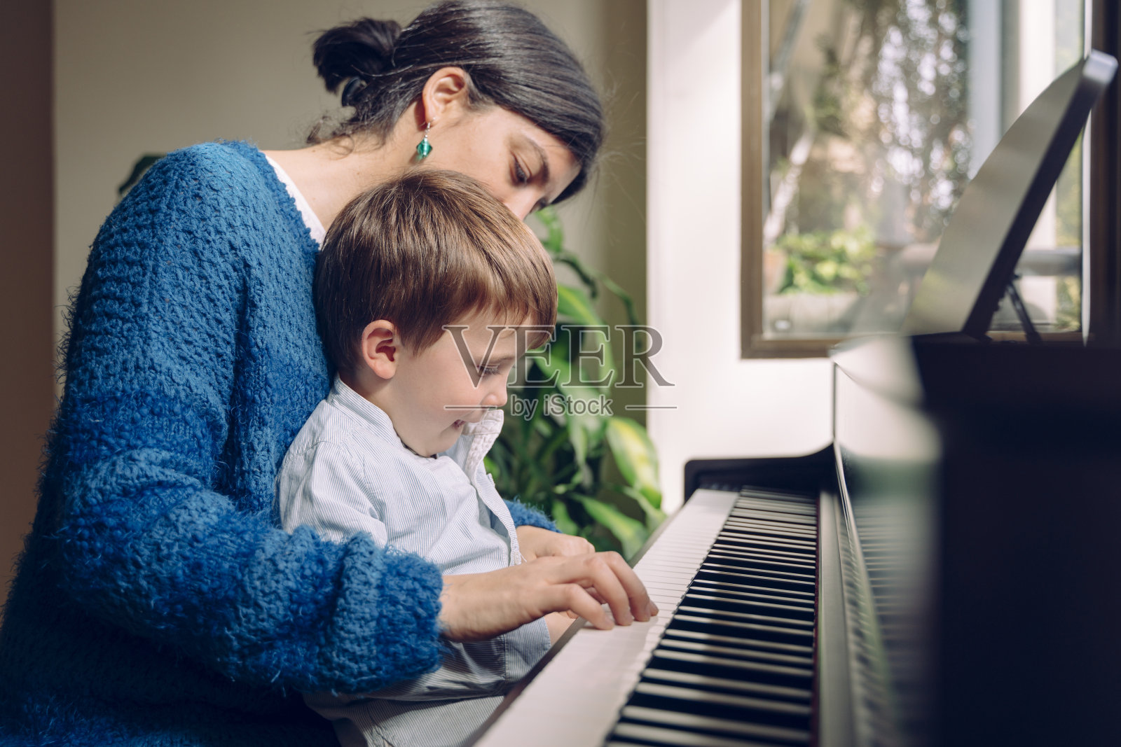 小孩子的教育音乐活动：妈妈在家教儿子钢琴课照片摄影图片
