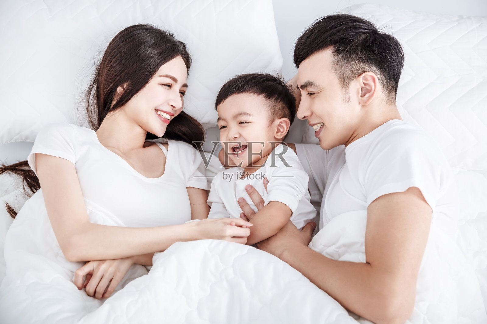 幸福的家庭一起躺在卧室的床上照片摄影图片