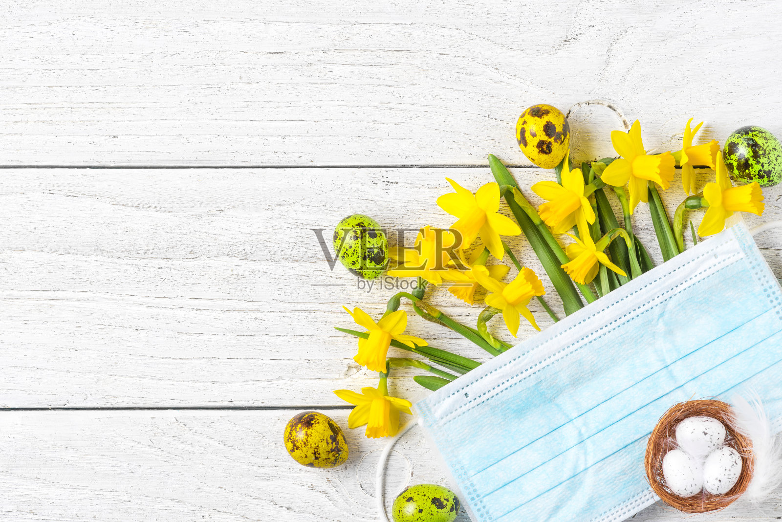复活节期间的冠状病毒隔离。春天的水仙花带着面膜和鸡蛋。模拟了照片摄影图片