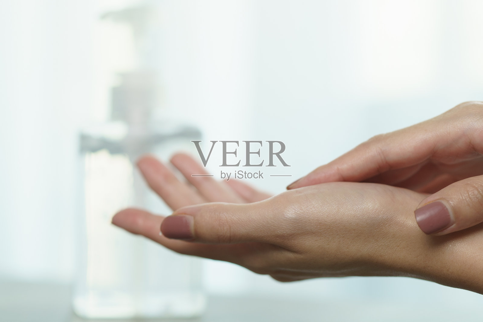 女性双手使用洗手液洗手液泵分配器。泵瓶内装有清洁消毒剂，用于杀菌、细菌和病毒。照片摄影图片