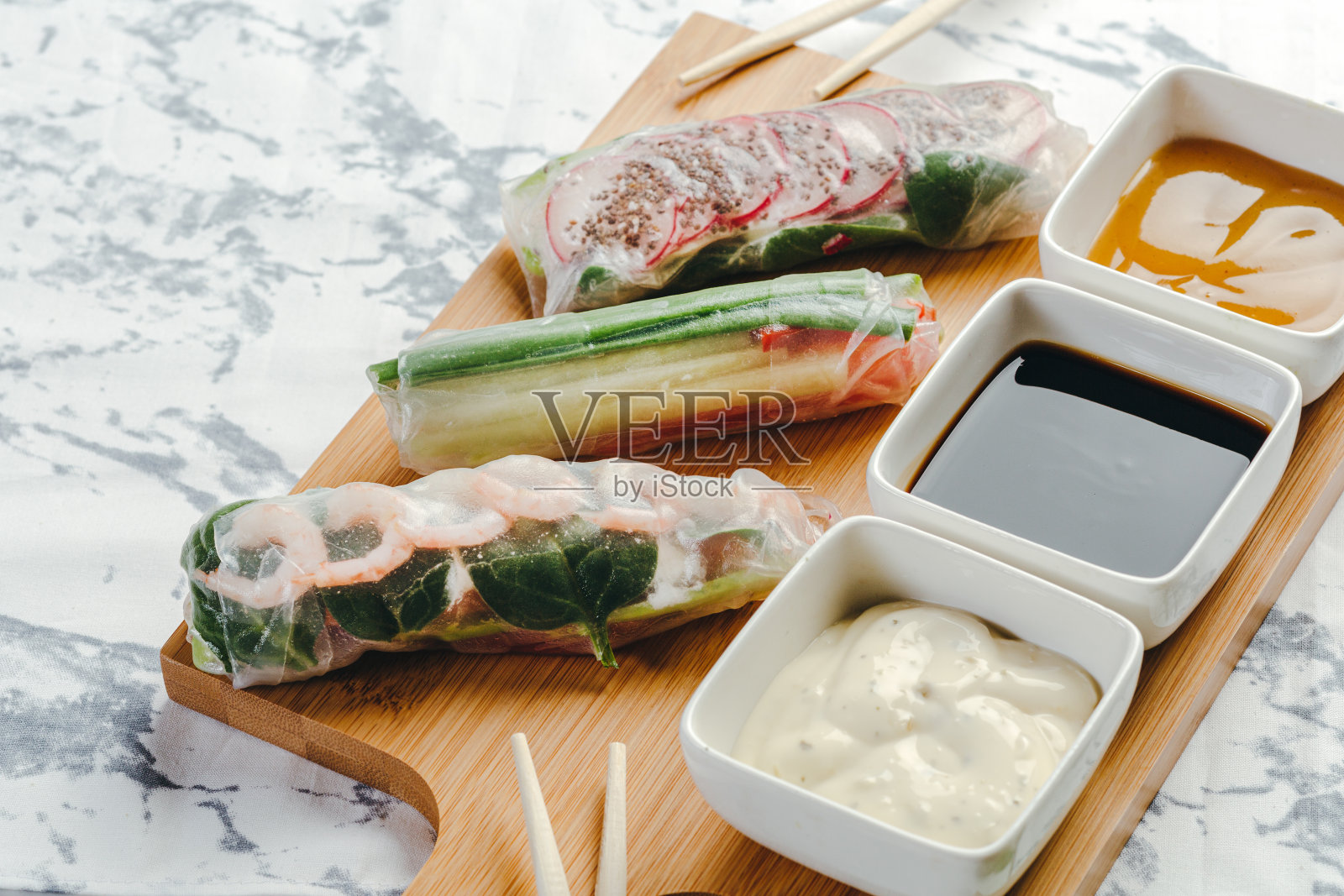 美味的春卷配虾仁、蔬菜和酱料，盛在木盘上，配上筷子。照片摄影图片