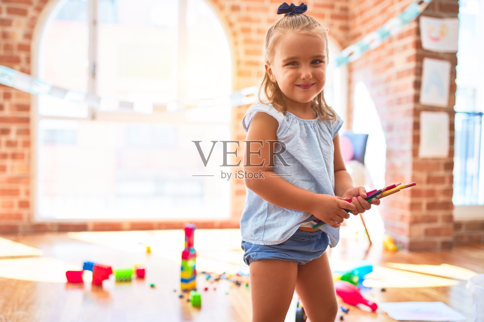 年轻漂亮的金发女孩孩子喜欢玩学校的玩具在幼儿园，微笑着幸福的绘画与铅笔的颜色在家里照片摄影图片