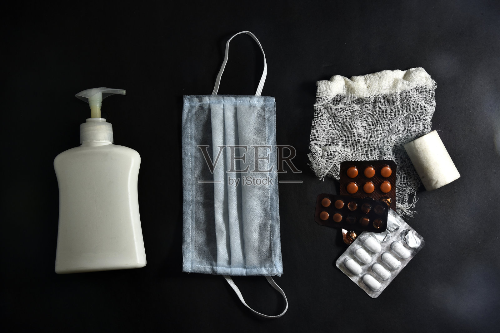 医用防护口罩和消毒剂，黑色背景，俯视图。冠状病毒爆发的防御。防冠状病毒的消毒剂和洗手液。照片摄影图片