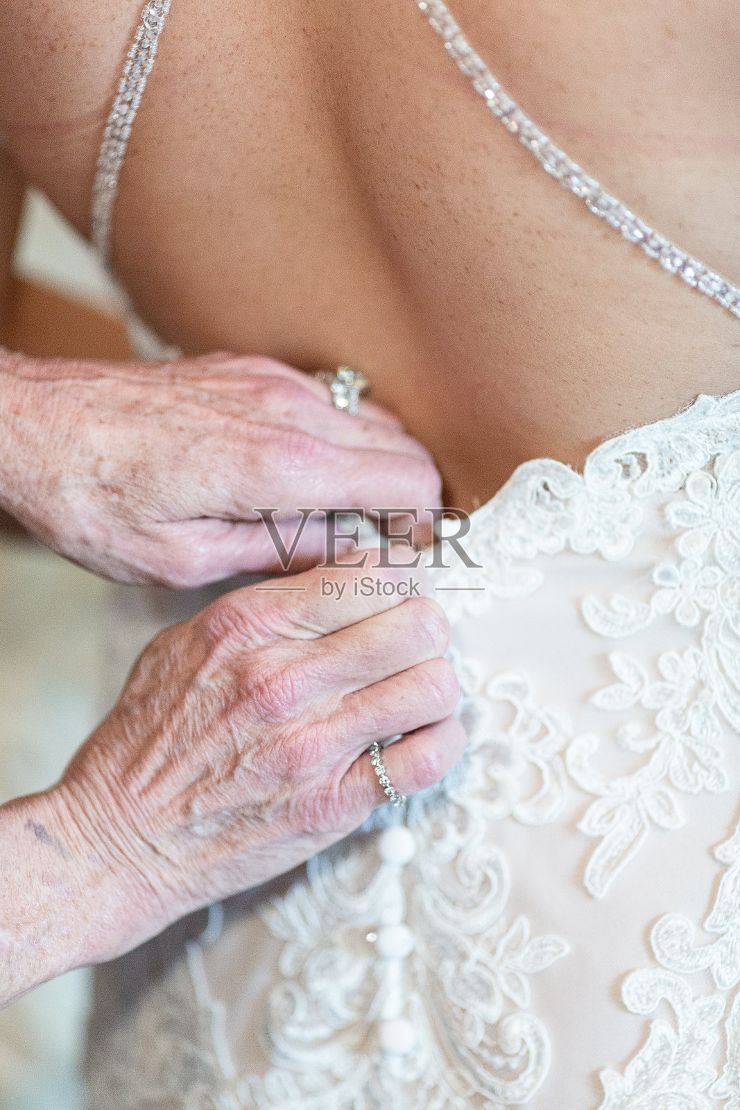 年长的手帮助新娘穿礼服-近距离照片摄影图片