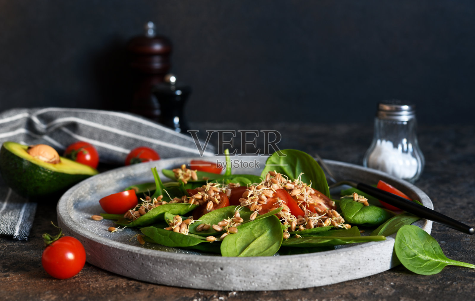 把菠菜、西红柿和小麦幼苗放在混凝土盘子里做成沙拉。照片摄影图片