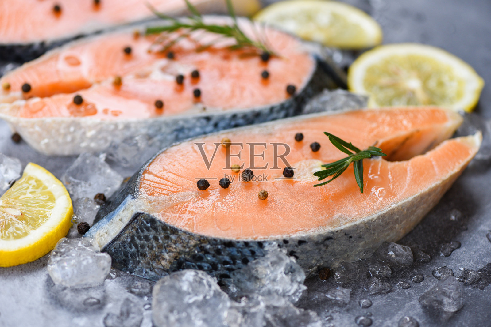 新鲜的生鲑鱼排与香草迷迭香在黑色的盘子背景照片摄影图片