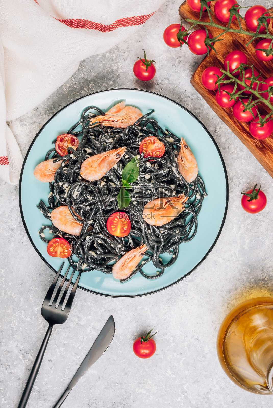 黑色意大利面配海鲜。传统的意大利菜-意大利面，虾，番茄和罗勒在陶瓷盘子在乡村的背景。平躺，俯视图。照片摄影图片