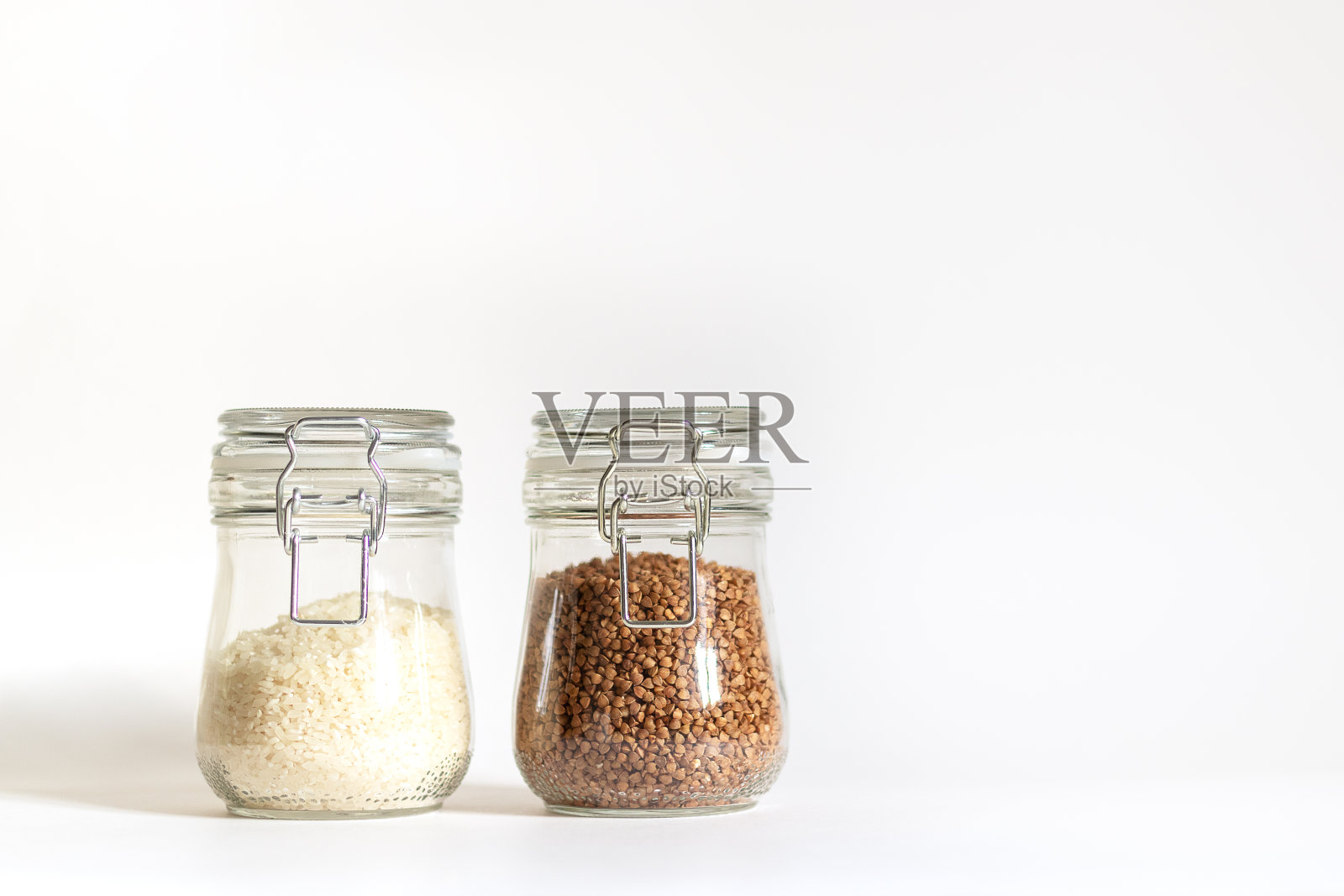 大米和荞麦紧紧地关在一个玻璃容器里。谷物储存在银行里。素食主义和其他饮食的健康食品。安全环保的食物储存。空间设计的极简主义照片摄影图片